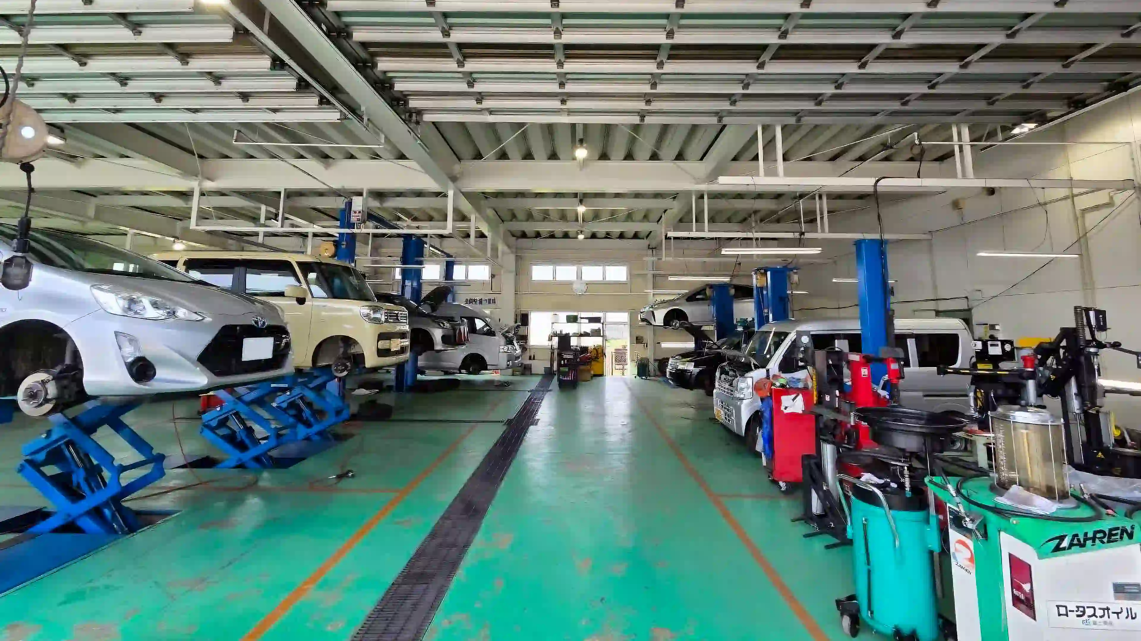 複数のリフトに自動車が載せられ、整然と管理されたクリーンな自動車整備工場の様子
