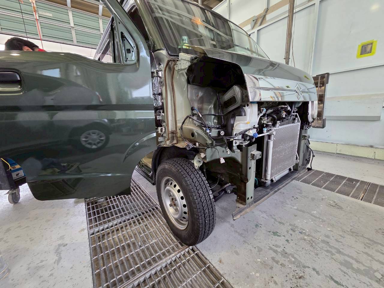 前方が大きく大破し、バンパーやフェンダーが外された状態の事故車